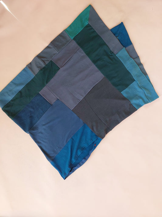 Close up detail view of the geometric panels and folded edges on the aqua teal upcycled merino wool poncho, highlighting the premium textile texture.