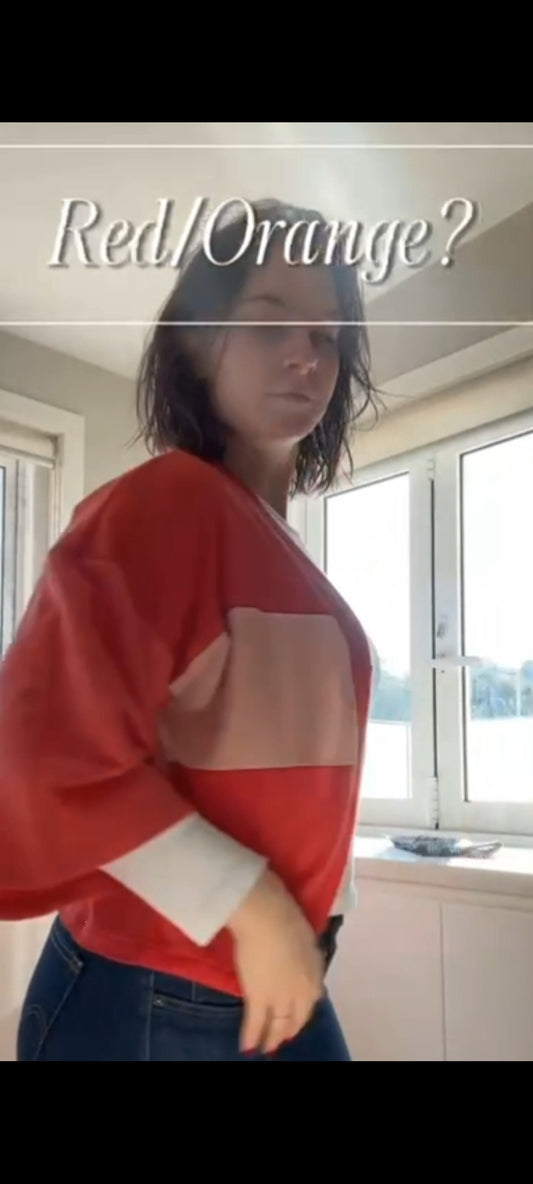 young lady wearing an ornage coral coloured cardigan standing in kitchen