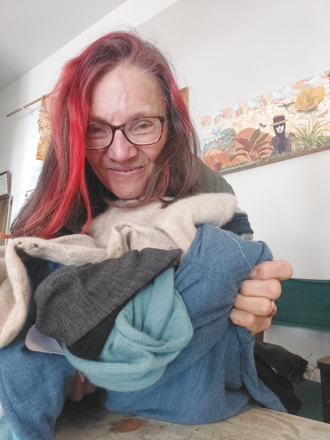 Heke Design Upcycling expert Bea Lorimer froholding an armful of merino sweaters, ready to upcycle