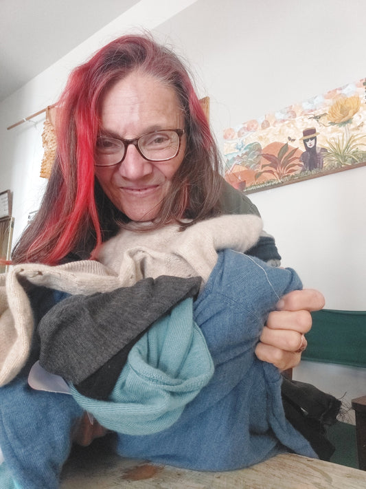 Heke Design Upcycling expert Bea Lorimer froholding an armful of merino sweaters, ready to upcycle