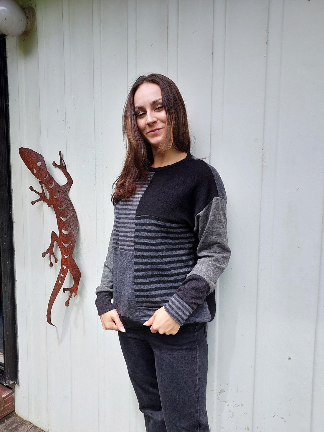 Woman wearing an upcycled merino sweater that has grey-toned stripes with a black block