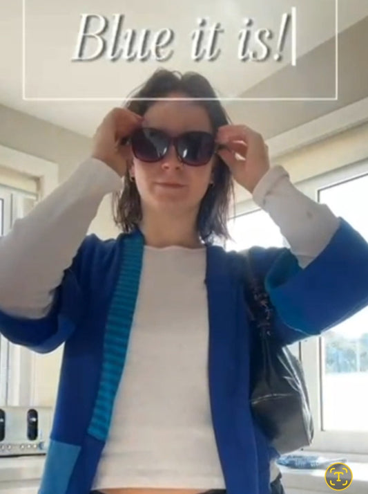 Person wearing a blue cardigan and sunglasses indoors with text 'Blue it is!'.