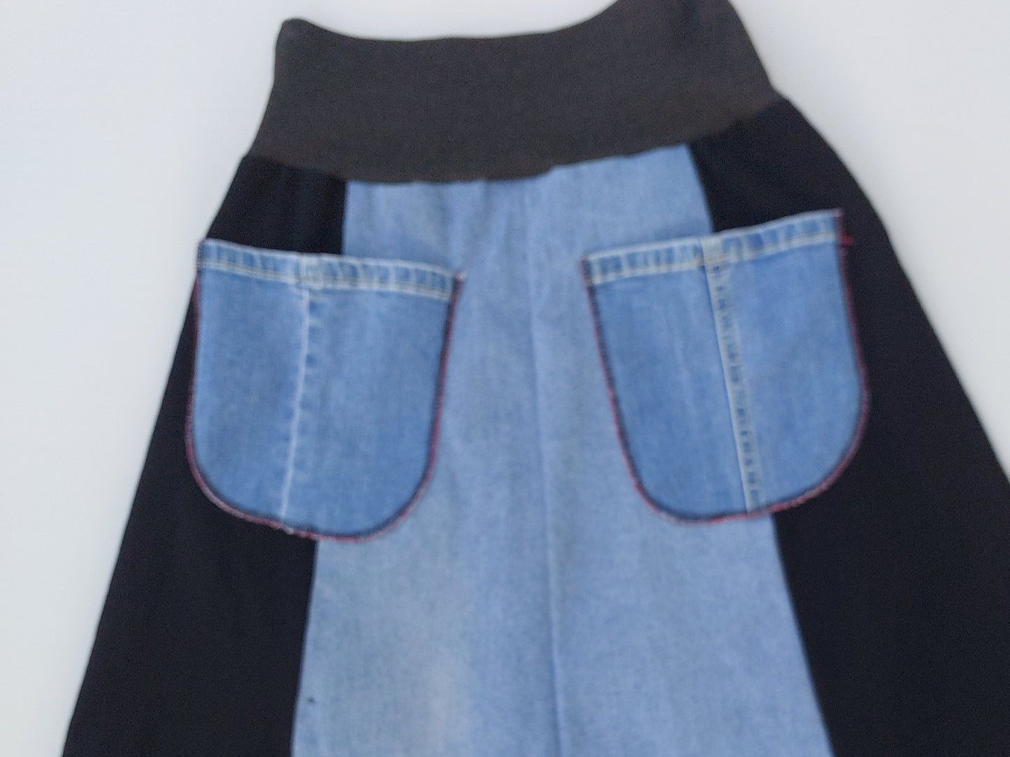 Reverse view of the upcycled denim skirt showing functional back pockets and tonal blue denim construction.