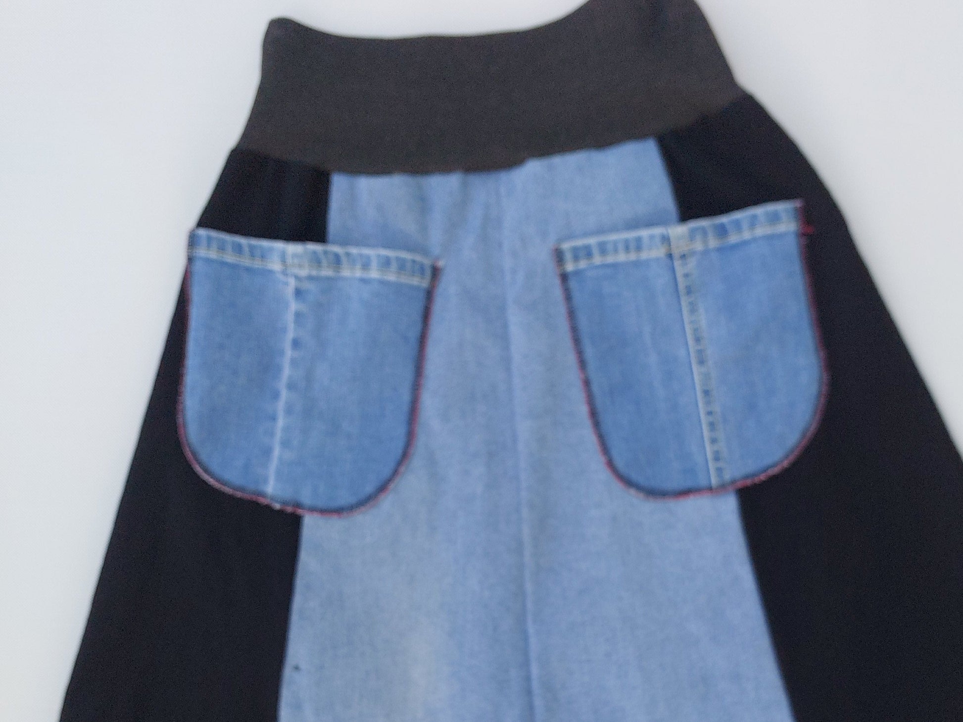 Reverse view of the upcycled denim skirt showing functional back pockets and tonal blue denim construction.